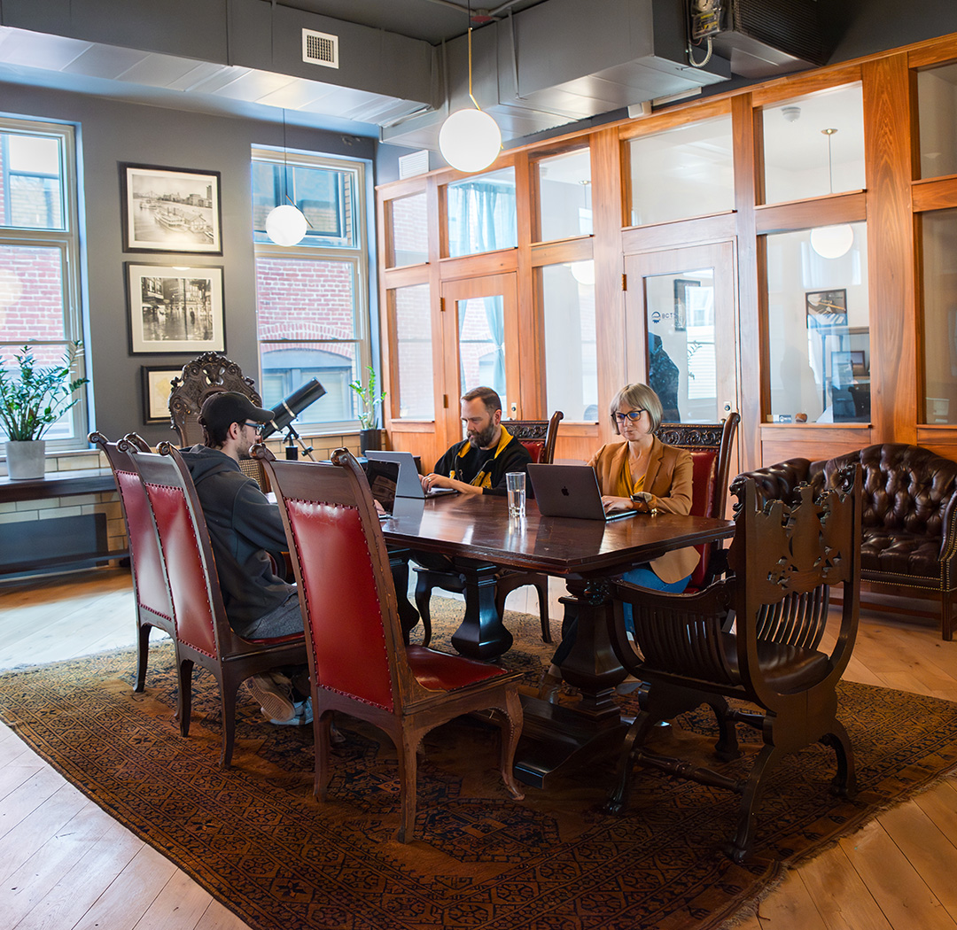 The Library Room at Fulton Commons coworking space Pittsburgh — antique table and leather seating with brick-view windows
