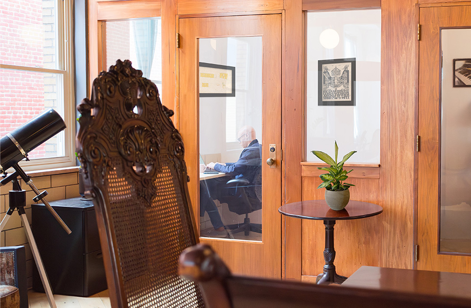 Member working in a private office with a glass door at Fulton Commons in Pittsburgh's Manchester neighborhood