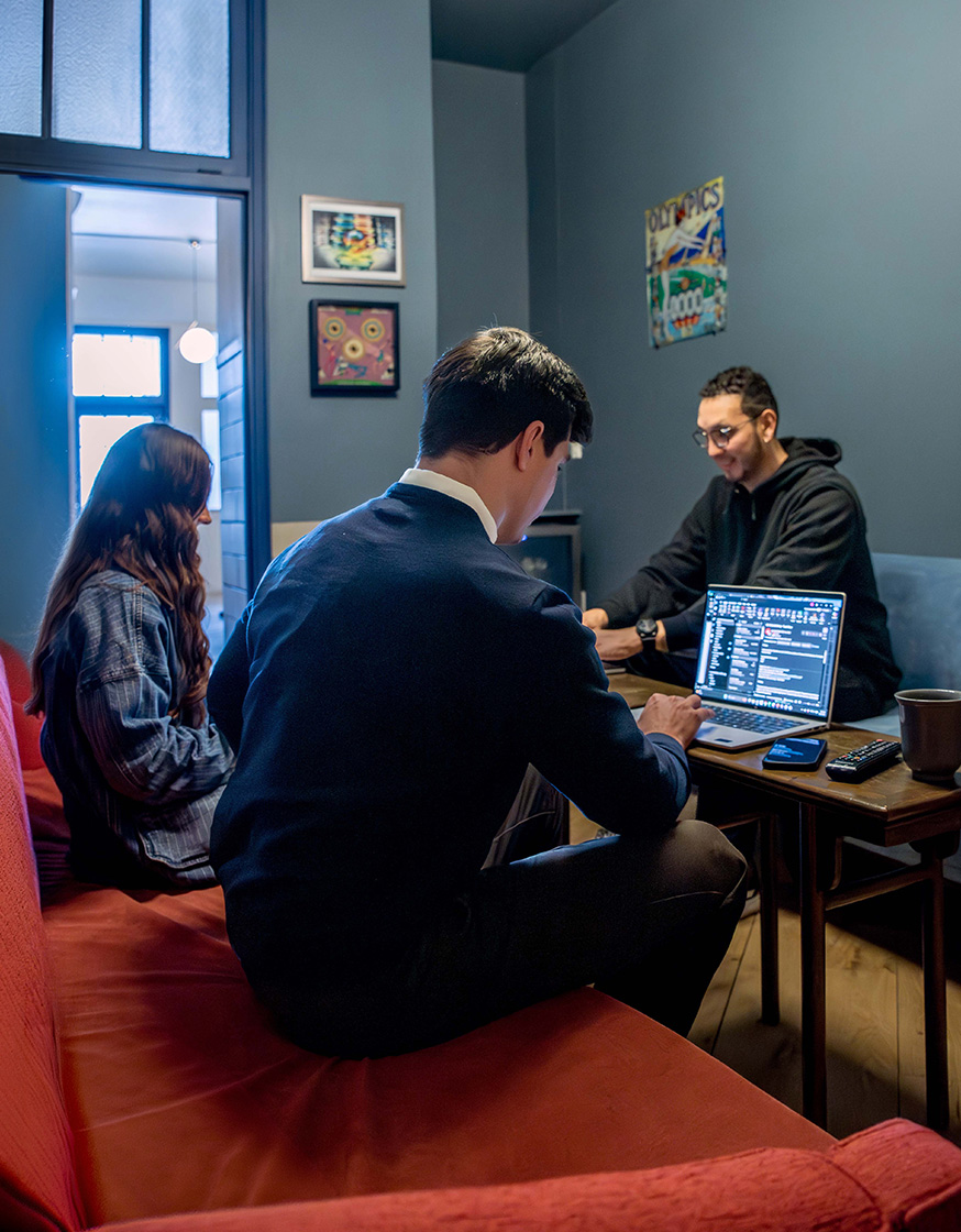 Three members working and talking together in a lounge at Fulton Commons Pittsburgh
