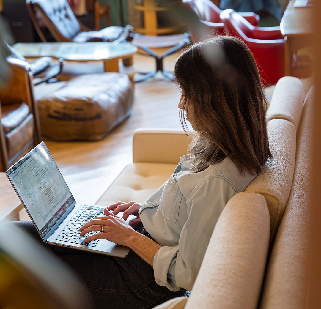 Member working on a laptop in a lounge chair at Fulton Commons Pittsburgh